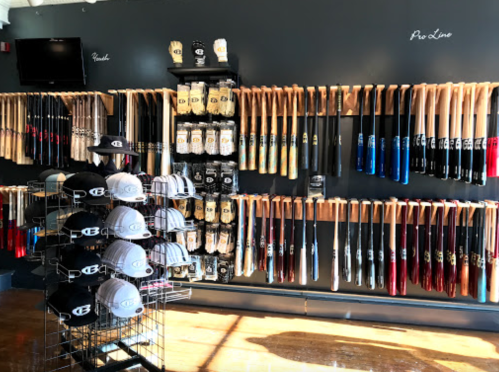 A display of baseball bats and caps on a wall, showcasing various brands and styles in a sports store.