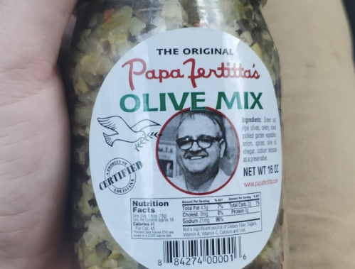 A jar of Papa Fertitta's Olive Mix featuring a label with a black-and-white photo of a man and ingredient details.