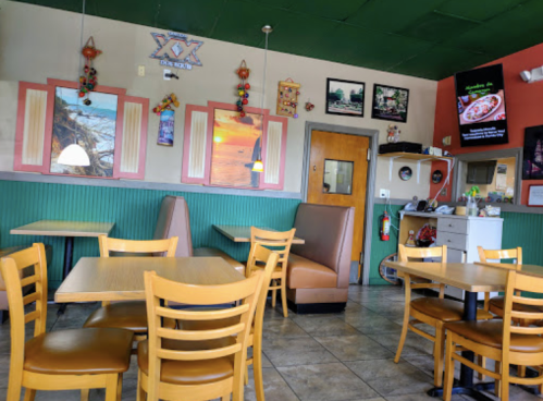 A cozy restaurant interior with wooden tables, green walls, and colorful decor, featuring booths and wall art.