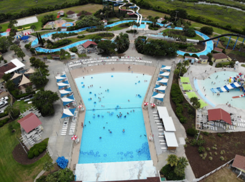 Aerial view of a water park featuring pools, slides, and lounging areas with people enjoying the water.