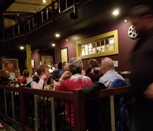 A dimly lit restaurant scene with diners at tables, enjoying their meals and drinks in a cozy atmosphere.