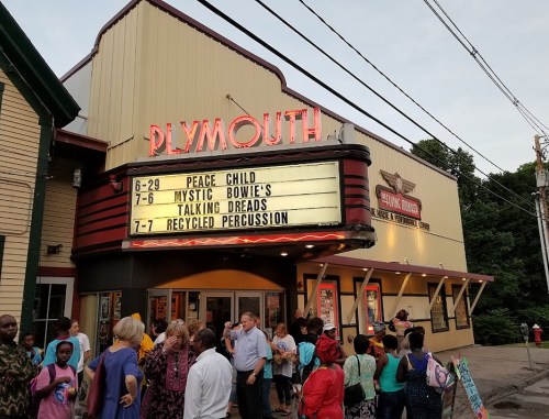 Plymouth theater marquee displaying upcoming events with a crowd gathered outside.