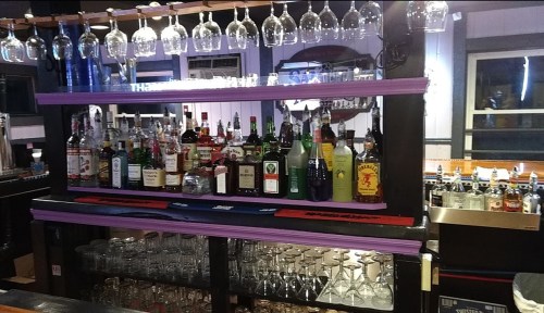 A well-stocked bar with various bottles of liquor and hanging glasses on display.