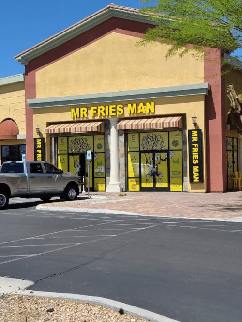 Exterior of a restaurant named "Mr Fries Man," featuring bright yellow signage and a parking lot with a truck.