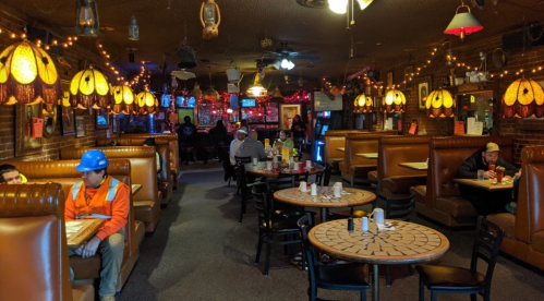 Cozy restaurant interior with booths, warm lighting, and patrons dining and working on laptops.