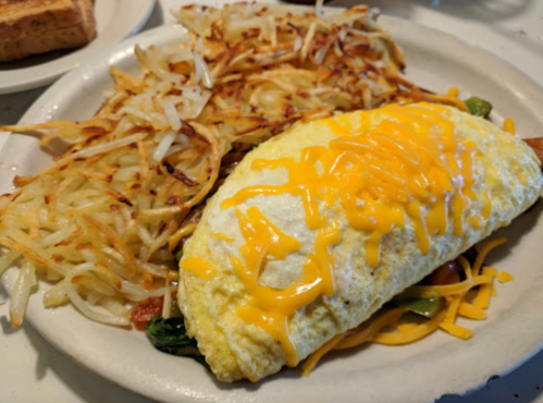 A plate featuring a cheese omelet with hash browns and toast on the side.