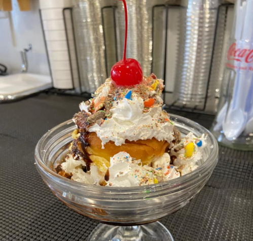 A delicious ice cream sundae topped with whipped cream, sprinkles, and a cherry, served in a glass bowl.
