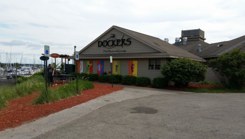 Exterior of Dockers restaurant with colorful murals, surrounded by greenery and a marina in the background.