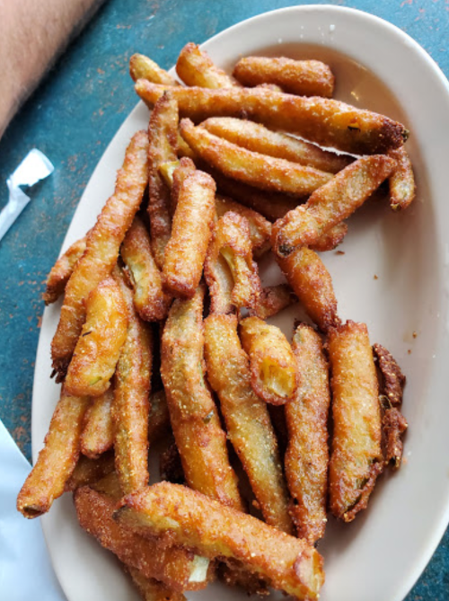 A plate of golden-brown, crispy fried green beans arranged neatly.