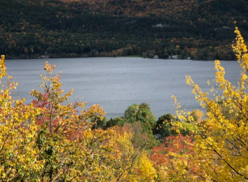 A serene lake surrounded by vibrant autumn foliage in shades of orange, yellow, and green.