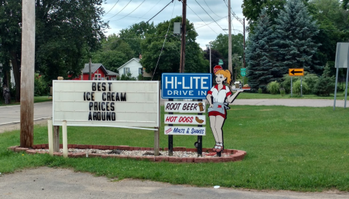 Sign for Hi-Lite Drive-In featuring ice cream, root beer, and hot dogs, with a vintage waitress illustration.
