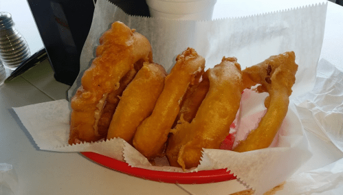 A plate of golden-brown fried dough, arranged neatly on a bed of white paper.