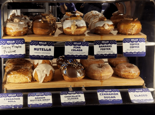 A display of assorted donuts with labels, including flavors like Nutella, Pina Colada, and Cinnamon Sugar.