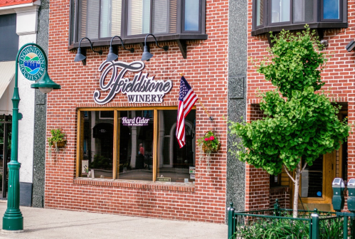 Exterior of Fieldstone Winery with a brick facade, American flag, and hanging flower baskets.