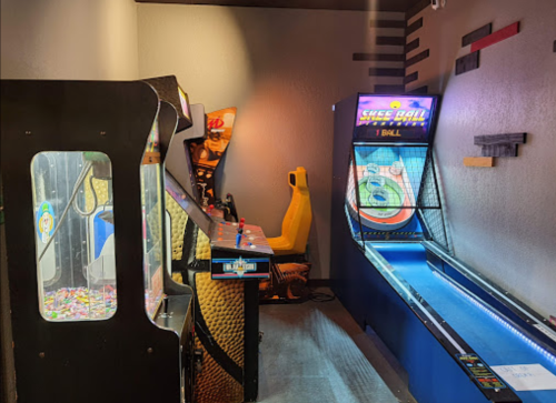 A cozy arcade corner featuring a skee-ball machine and a candy crane game in a vibrant setting.