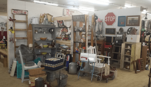 A vintage shop interior filled with various antiques, including shelves, signs, and decorative items.
