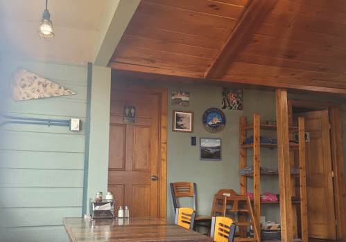 Cozy interior of a café with wooden walls, art on the walls, and a table set for dining.