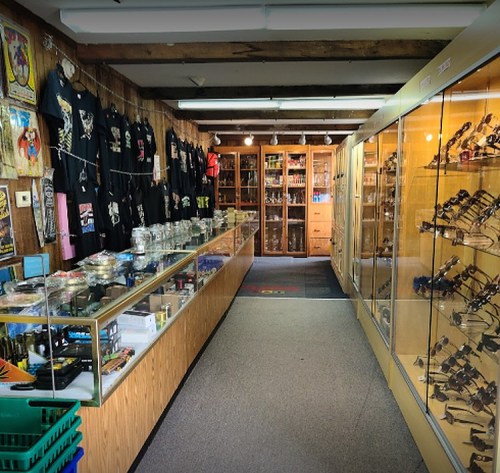 Interior of a shop featuring display cases with various items, t-shirts on the wall, and a clean, organized layout.
