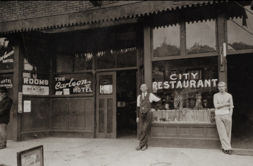 Historic photo of the Carbon Hotel and City Restaurant, featuring two men standing outside the entrance.