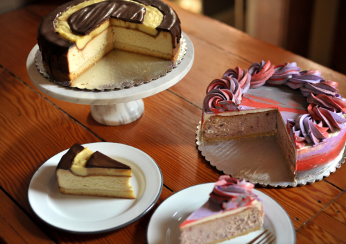 A display of two cakes: one layered with chocolate and cream, and another with colorful frosting, alongside slices on plates.