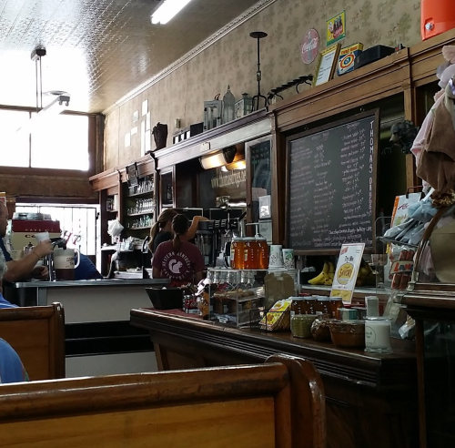A cozy café interior with wooden furniture, a chalkboard menu, and patrons enjoying their drinks.
