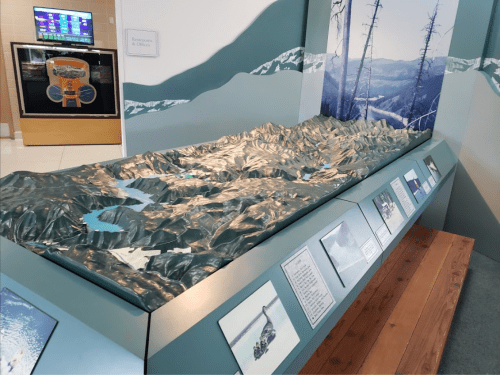 A 3D topographic model of a mountainous landscape displayed in an educational exhibit.
