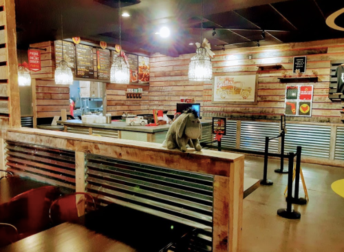 A cozy restaurant interior with wooden decor, a menu board, and a plush bunny sitting on the counter.