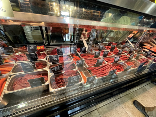A display case filled with various cuts of meat, labeled with tags, in a butcher shop.
