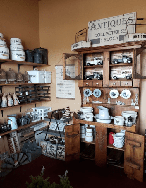 A cozy antique shop display featuring vintage items, a wooden hutch, and various collectibles on shelves.