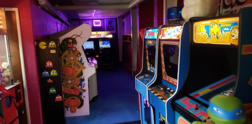 A colorful arcade hallway featuring classic arcade machines and vibrant wall art.
