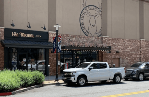 Exterior view of a building featuring "Punch Bowl Social" and "Van Michael Men" signs, with parked cars in front.