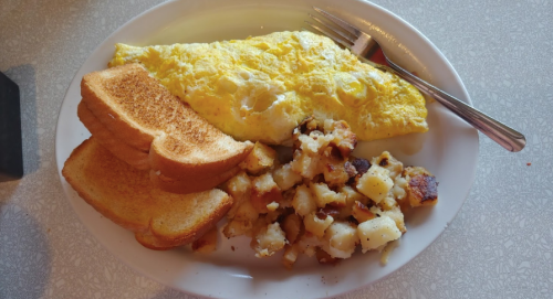 A plate of breakfast featuring an omelette, toast, and crispy hash browns.