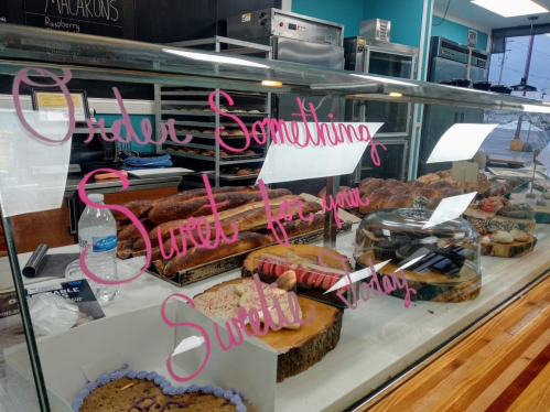 A display case filled with various baked goods, with a sign saying "Order Something Sweet for your Sweetie Today."