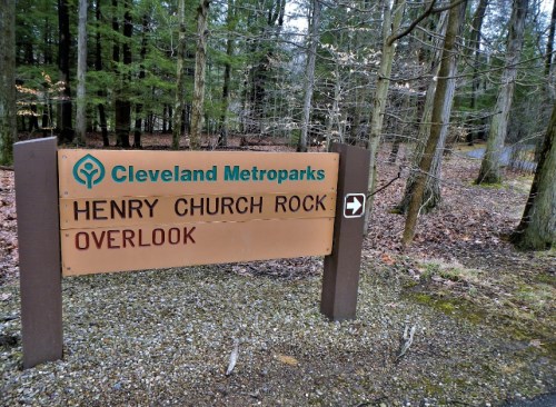 Sign for Henry Church Rock Overlook in Cleveland Metroparks, surrounded by trees and forested area.
