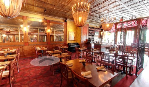 Elegant restaurant interior with wooden tables, chandeliers, and a warm color palette, featuring a cozy atmosphere.
