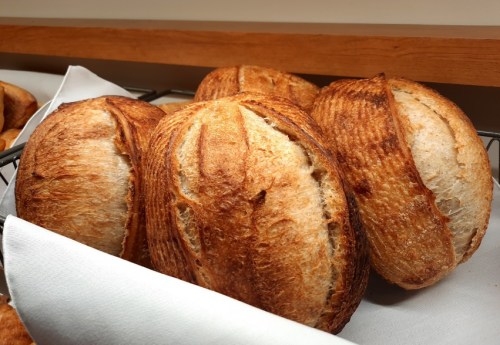 Freshly baked artisanal bread loaves resting on a white cloth in a basket.