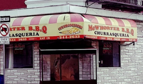 A storefront with a striped awning reading "McWhorter B.B.Q. Churrasqueria" and a sign indicating it's open.