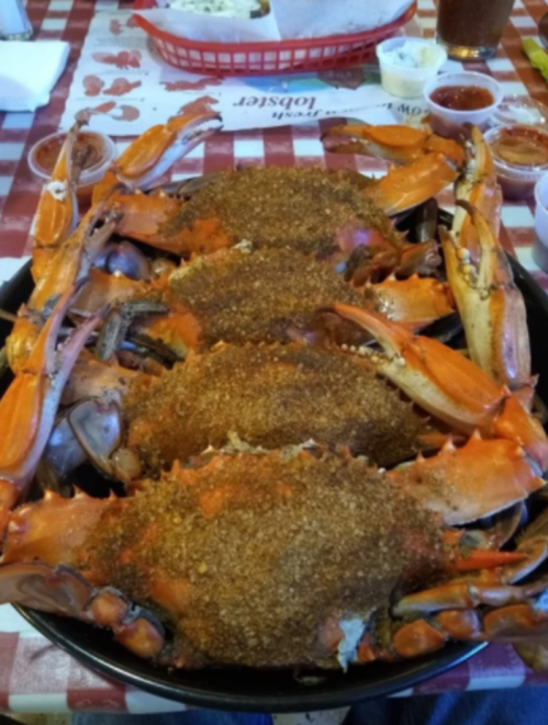 A large platter of seasoned crabs arranged neatly, served on a checkered tablecloth.