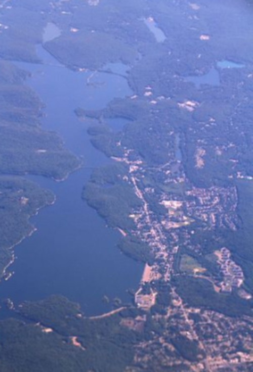 Aerial view of a winding river surrounded by lush greenery and small towns along the banks.