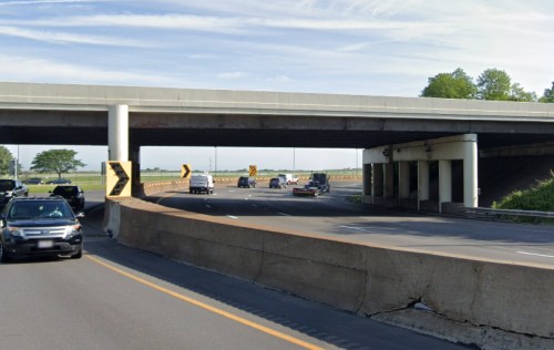 A highway interchange with vehicles navigating curved ramps under a concrete overpass on a clear day.