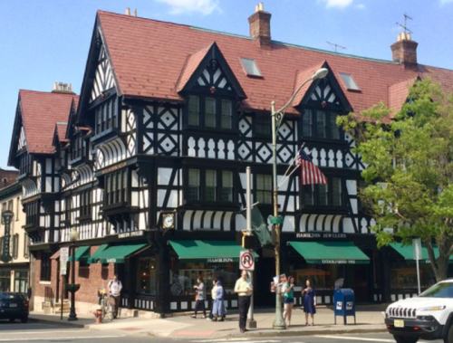 Historic building with Tudor-style architecture, featuring black and white timber framing and green awnings.
