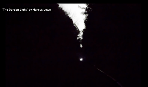 A dark scene featuring a faint light in the distance, surrounded by shadowy trees, titled "The Gurdon Light" by Marcus Lowe.