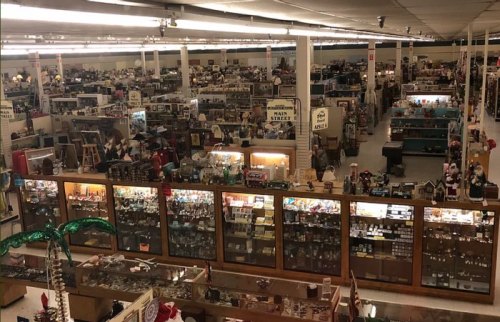 A wide view of a large antique store filled with various collectibles and displays under bright lights.