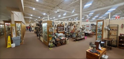 A spacious antique store aisle lined with display cases filled with vintage items and collectibles.