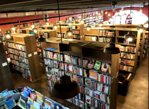 A cozy library filled with bookshelves, warm lighting, and reading areas, creating an inviting atmosphere.
