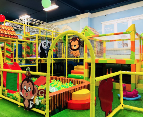 Colorful indoor play area with climbing structures, ball pits, and cartoon animal decorations. Fun for kids!