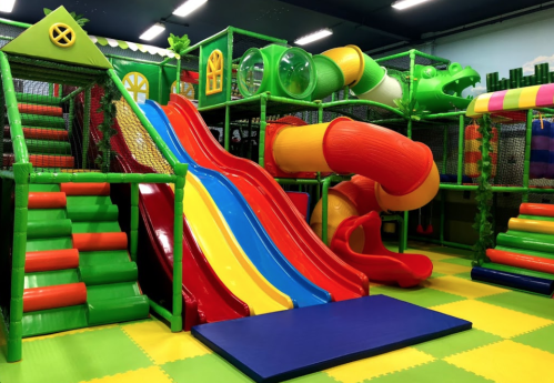Colorful indoor playground featuring slides, climbing structures, and tunnels in a vibrant, playful environment.