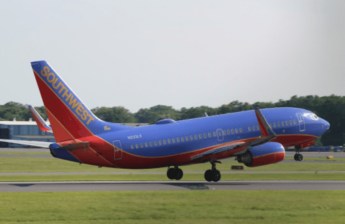 A Southwest Airlines airplane taking off on a runway with a clear sky in the background.