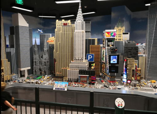 A detailed LEGO cityscape featuring skyscrapers, streets, and vibrant billboards, resembling a bustling urban environment.