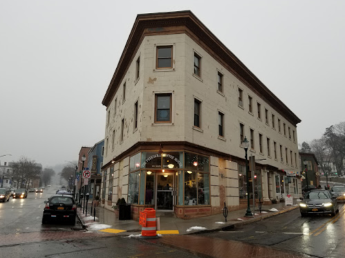 A corner building in a small town, featuring a café on the ground floor, with a foggy atmosphere and wet streets.